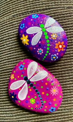 two painted rocks with flowers and dragonflies on them