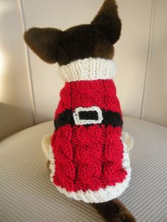 a small dog wearing a red and white knitted sweater with a santa clause on it's chest