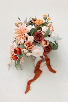 a bridal bouquet with orange and white flowers on a white background for an autumn wedding