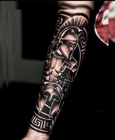 a man's arm with a black and grey tattoo design on the left forearm