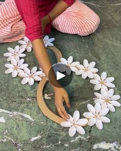 a woman sitting on the floor making a flower wreath