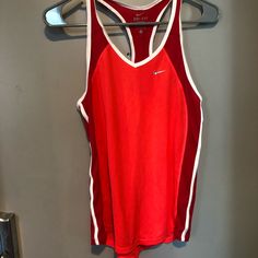 a red nike tank top hanging on a hanger