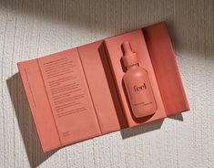 an open pink box containing a bottle of red liquid on top of a white carpet