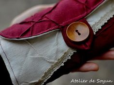 a woman's hand holding a red and white purse with buttons on the side