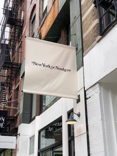 a sign hanging from the side of a building in new york city, with people walking by