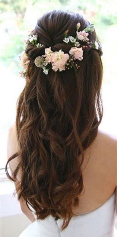 the back of a woman's head with flowers in her hair, looking out a window