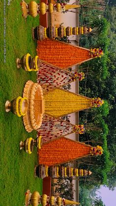 an outdoor wedding setup with orange and yellow decorations on the grass in front of trees