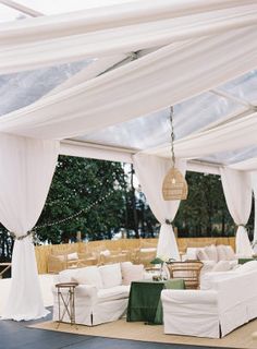 a white tent with couches and tables under it