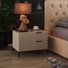 a teddy bear sitting on top of a night stand next to a lamp and bed