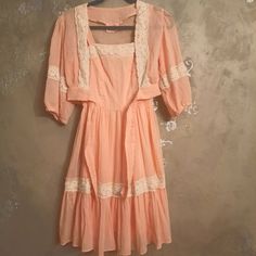 Vintage Darling Debs Tank Fit And Flare Midi Dress Beautiful Peachy Gauze Fabric With Lace Trim Fully Lined Zip Up Back Straps Unbutton To Be Cross Crossed Or Straight Matching Tie Front Bolero Ballon Sleeve Tie Front In Great Condition Please Reference Photos No Size Tags Fits Like An Xs Measures 47 Long 14 Across Chest 12 Across Waist Orange Feminine Dresses For Daywear, Pink Mini Length Vintage Dress For Summer, Orange Lace Trim Summer Dress, Pink Mini Vintage Dress For Summer, Summer Vintage Knee-length Dress With Lace Trim, Vintage Fitted Apricot Dress, Fitted Vintage Apricot Dress, Apricot Fitted Vintage Dresses, Vintage Orange Midi Dress For Summer