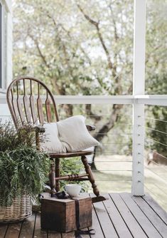 a rocking chair sitting on top of a wooden deck next to a potted plant