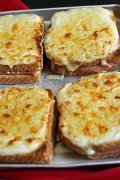 four toasted sandwiches with cheese and meat on them sitting on a pan, ready to be eaten