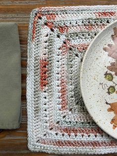 a crocheted place mat with a white plate on it and a gray napkin