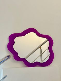 there is a purple mirror on the wall next to a stair railing and a hand rail