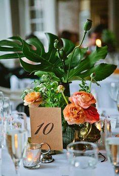 an arrangement of flowers and greenery in a vase with a table number on it