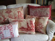 a bunch of pillows sitting on top of a white couch in front of a book shelf