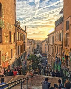 people are sitting on the steps in an alleyway with graffiti painted on the walls