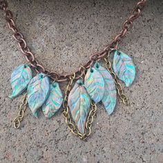 a close up of a necklace with leaves on it