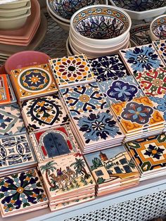 many different colored tiles are on display at a market table with bowls and plates in the background