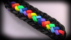 a rainbow - colored braided bracelet is shown on a white background with black leather