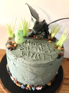 a birthday cake decorated with green frosting and an image of a dragon on top