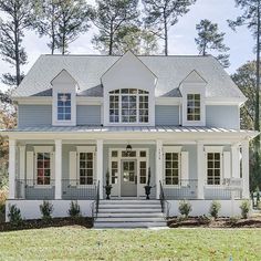 a white house with blue trim and two storys on the front, surrounded by trees