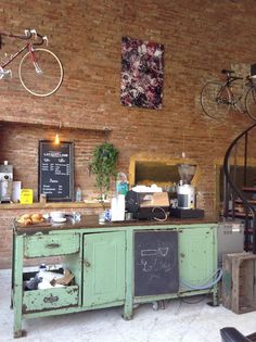 a coffee shop with an old green cabinet and spiral staircase in the back ground, next to a brick wall