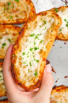 someone is holding up some bread with cheese and parsley on it in their hand