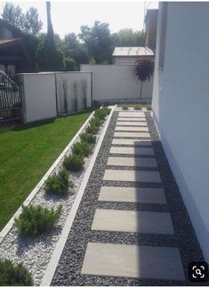 a white fenced in area with grass and rocks on the ground next to it