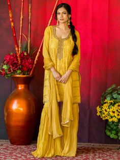 Introducing the stunning Vinita Sharara - a perfect blend of elegance and style to make you stand out at any event or occasion. With its beautiful golden yellow color and exquisite craftsmanship, this women's suit is designed to make you look and feel fabulous. Key Features: Perfect for events, festive occasions, ceremonies, and parties Fusion of traditional and western styles for a unique indo-western look Made with high-quality materials for long-lasting durability Designed to flatter your fig Festive Yellow Embroidered Sharara, Elegant Yellow Embroidered Sharara, Fitted Yellow Sharara With Intricate Embroidery, Transitional Yellow Embroidered Sharara, Embroidered Semi-stitched Orange Sharara, Buy Lehenga Online, Indian Bridal Couture, Reception Gowns, Elegant Veils