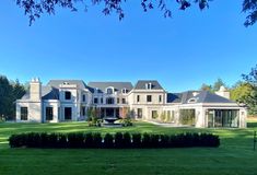 a large white house sitting in the middle of a lush green field with lots of trees