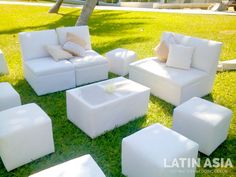 a bunch of white couches and ottomans in the grass