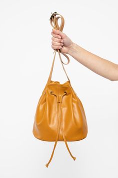 The Drawstring Bucket Bag is a classic that combines style and function. You’ll find that this spacious bag fits easily into your daily wardrobe. This artisanal product is made of genuine leather. All scars are characteristics of the skin and not imperfections. We hope you enjoy this unique handmade object. | Drawstring Bucket Bag for Women in Dijon Leather Pouch For Shopping, Everyday Cognac Bucket Bag With Detachable Strap, Cognac Bucket Bag With Dust Bag Included, Daily Use Bucket Pouch With Detachable Strap, Chic Leather Pouch With Adjustable Strap, Leather Bucket Pouch For Shopping, Cognac Bucket Bag With Dust Bag For Travel, Leather Lining Bucket Bag, Everyday Use Bucket Pouch With Adjustable Strap