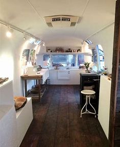 the inside of an rv with wood flooring and white appliances on it's walls