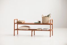 a wooden table with a basket on top and some books sitting on the shelf next to it