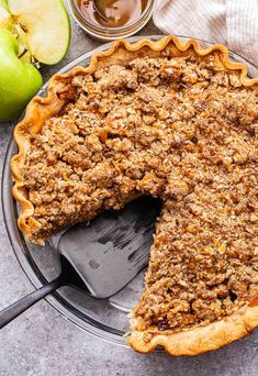 an apple crumbled pie on a plate with a slice missing from the pie