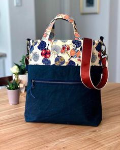 a handbag sitting on top of a wooden table next to a potted plant