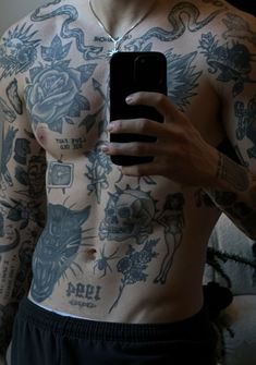 a man with tattoos on his chest holding a cell phone