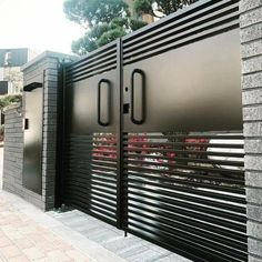 the gate is made of metal and has red flowers on it, along with two black doors