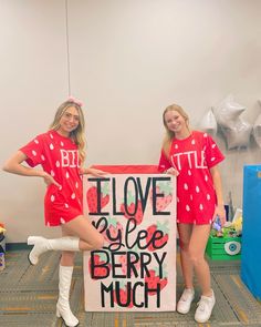 two girls in matching red shirts holding a sign that says i love you are berry much