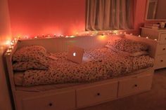 a laptop computer sitting on top of a white bed in a room with pink walls