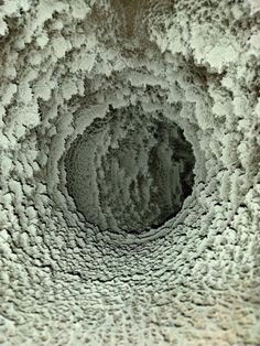 the inside of a circular hole with clouds and water in it, as seen from below