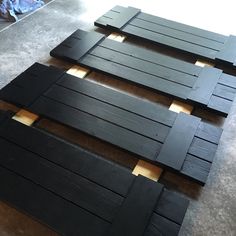 three pieces of black wood sitting on top of a floor