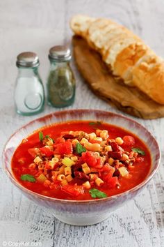 a bowl of tomato soup with bread on the side