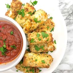 a white plate topped with tater tots covered in sauce and garnished with parsley