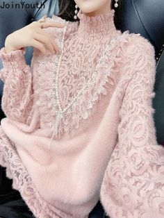 a woman sitting in a chair wearing a pink sweater and pearl necklace with pearls on her neck