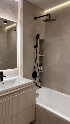 a bathroom with a bathtub, sink and shower head is shown in this image