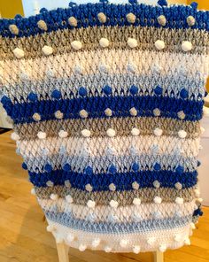 a blue and white crocheted blanket sitting on top of a wooden table