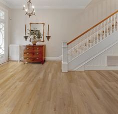 an empty room with wooden floors and white railings on the wall, next to a staircase