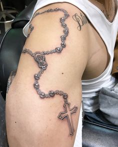 a man with a cross tattoo on his arm and rosary attached to the back of his arm